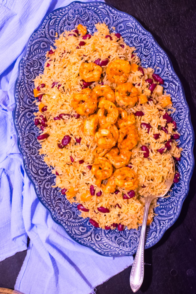 Overhead shot of a platter of red beans and coconut rice topped with shrimp.