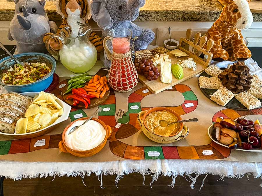 Game night food table set up to look like a Jumanji board game with stuffed jungle animals. 