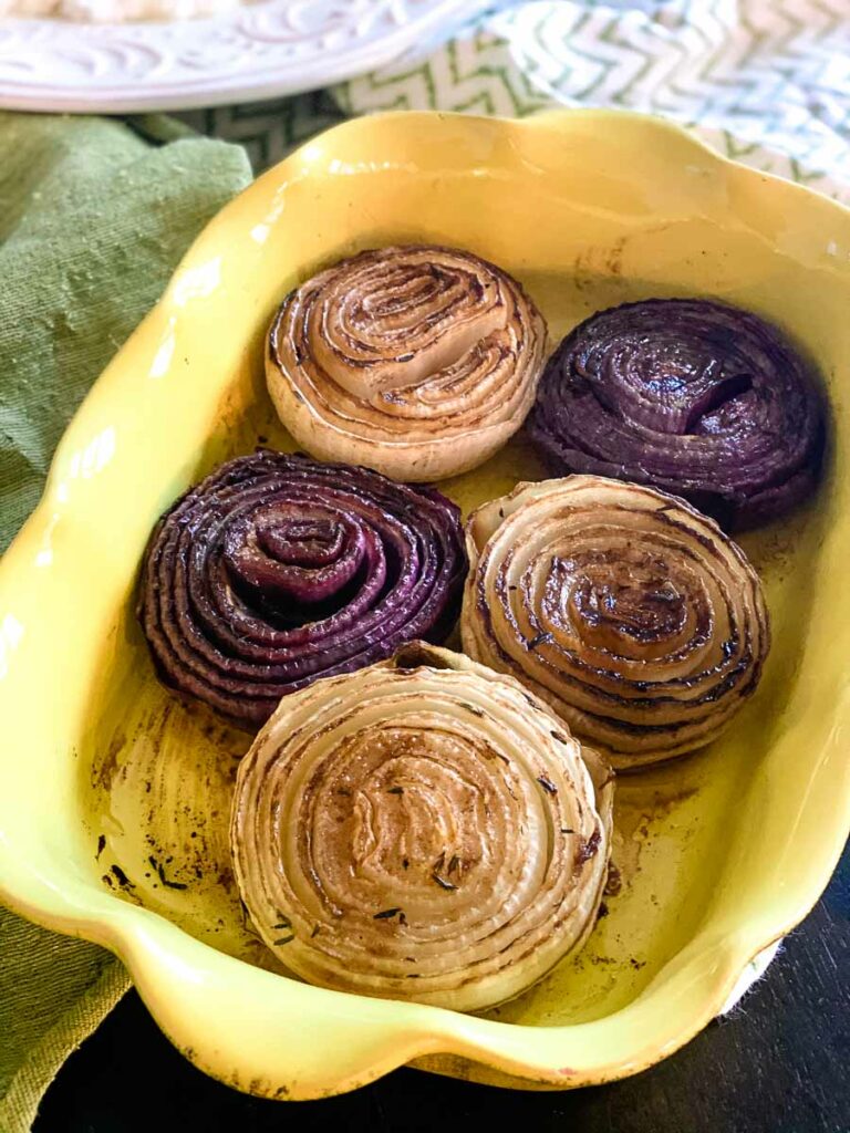 Roasted white and purple onions in a yellow baking dish.