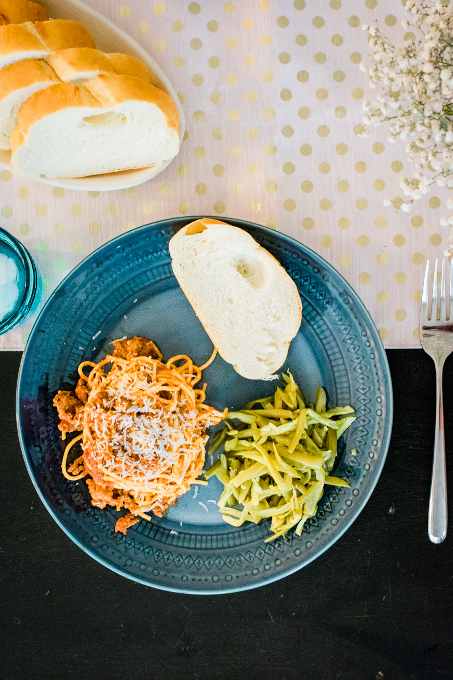 overhead view plate of spaghetti, green beans, and french bread