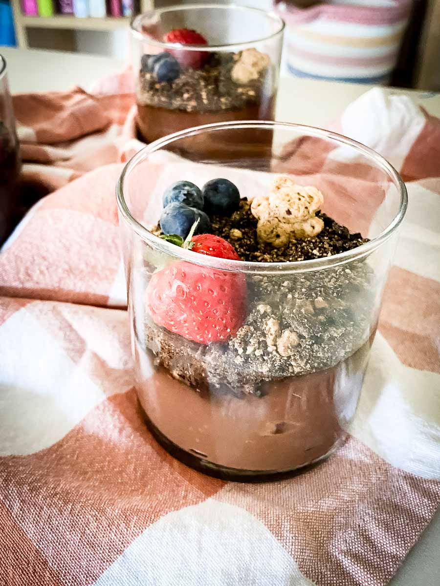 Clear glass filled with layers of chocolate pudding, crushed cookies, and fresh fruit